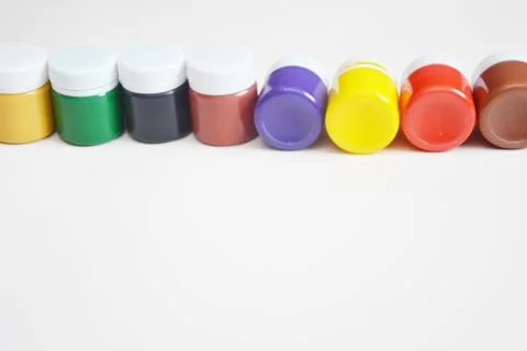 Closed jars of colored gouache, lying in a row on a light background. Multi-c Foto stock