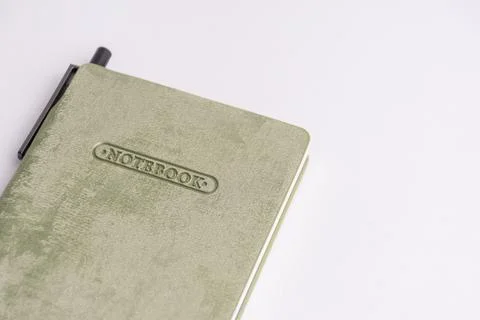 Closed light green cover notebook with a grey pen resting on it isolated on.. Stock Photos