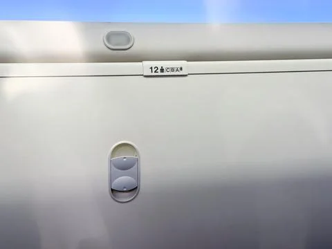 Closed overhead locker inside airplane cabin with seat number label visible.  Stock Photos