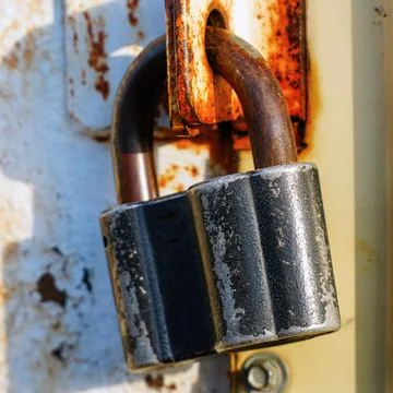 Closed padlock hanging on the hinges Stock Photos
