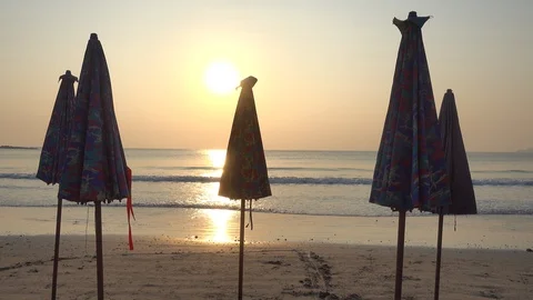 Closed parasols on an empty beach with the ocean in the background. Golden Stock Footage 104671964