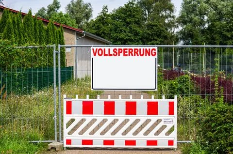A closed path with a barrier and a construction fence with a rectangular board Stock Photos