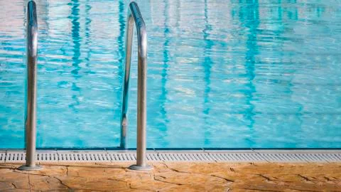 Closed plan of a pool ladder with the pool in the background. Stock Photos