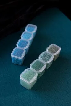 Closed plastic containers filled with colored beads Stock Photos