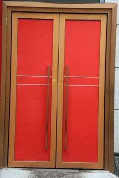 Closed red double doors with bronze frame and long vertical handles Stock Photos