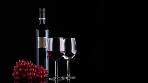 Closed red wine bottle with empty label, grape and two glasse Stock Photos