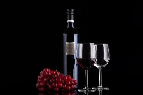 Closed red wine bottle with empty label and small branch of grape Stock Photos