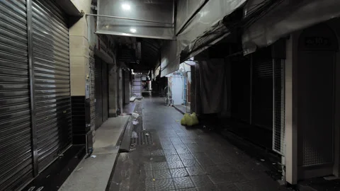 Closed shops and dim narrow passage at Sampeng market, man on motorbike ride by Stock Footage 326376169