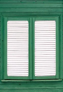 Closed shutter on old white timber window on green wooden building Stock Photos
