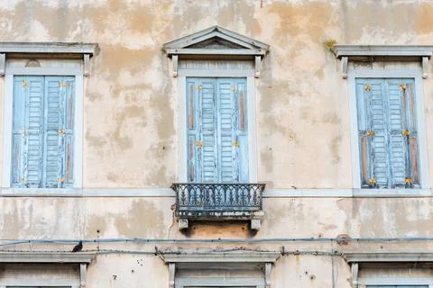 Closed shutters on the windows of a dilapidated building in the historic centre. Фото