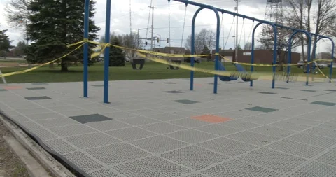 CLOSED sign in front of a Playground, Caution Tape Blowing in the Wind - Pan Stock Footage 128783126