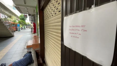 Closed sign at storefront during New Year holiday with pedestrian walking - day Stock Footage 197100767