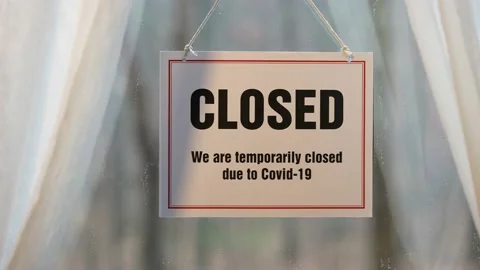 Closed sign swinging in the window of store front display in business concept. Video stock 143146600