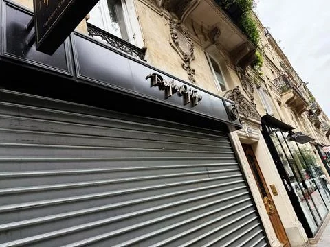 Closed storefront with metal roller shutter on Paris building facade, France Stock-Fotos