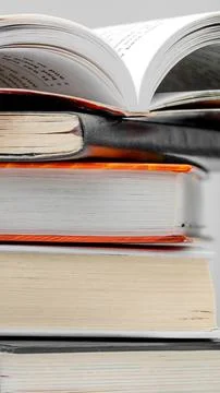 Closed thick education textbooks stacked neatly beneath a single large open.. Stock Photos