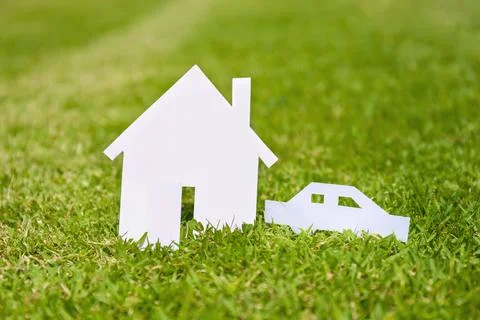Closed up tiny home and car model from white paper on green grass background Stock Photos