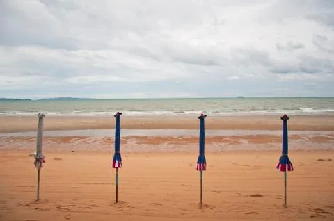 Closed  umbrellas on the beach Stock Illustration