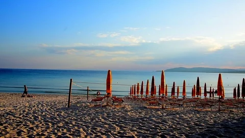 Closed umbrellas by the shore at sunset. Video stock 76516193