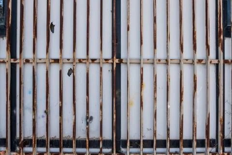 Closed white bars rusty metallic gate detail. Stock Photos