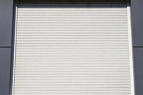 Closed white metal roller shutter door on a building Stock Photos