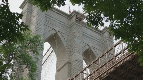 Closer low angle view of Brooklyn Bridge tower framed by fluttering leaves Stock Footage 340862414