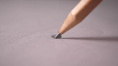 Closer view of the point of a pencil drawing a small black circle on a paper Stock Footage 160564330