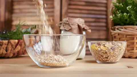 Closeup adding cereal granola oatmeal into bowl cooking healthy dieting Stock Footage 165868772