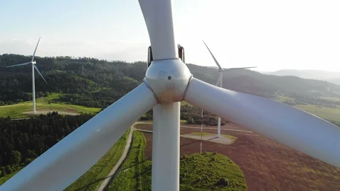 Closeup aerial view of wind turbine blades rotating around with beautiful green Stock Footage