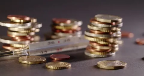 Closeup of Analog Thermometer between piled up Coins. healthcare cost in Euro Stock Footage 147936413