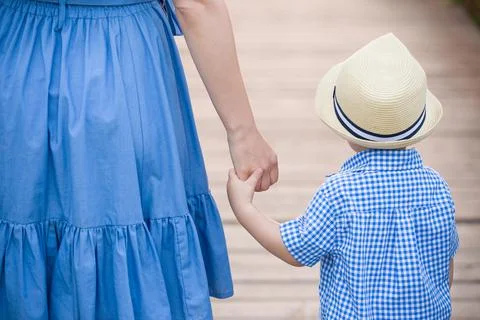 Closeup and back view on cute little toddler boy in straw hat holding his mot Stock Photos