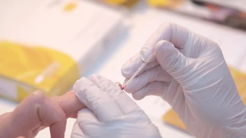 Closeup anonymous medical practitioner in latex gloves piercing finger and Vidéo 122425467