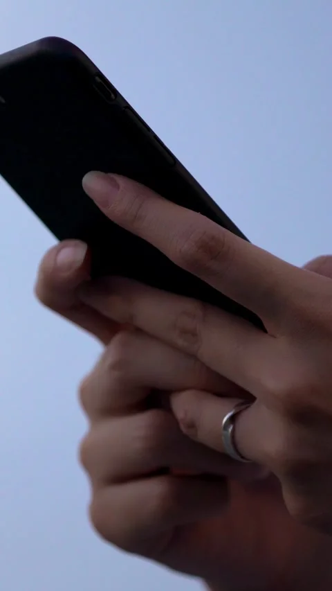 Closeup of asian hand using her smartphone in street at day with blue sky Stock Footage 330926485