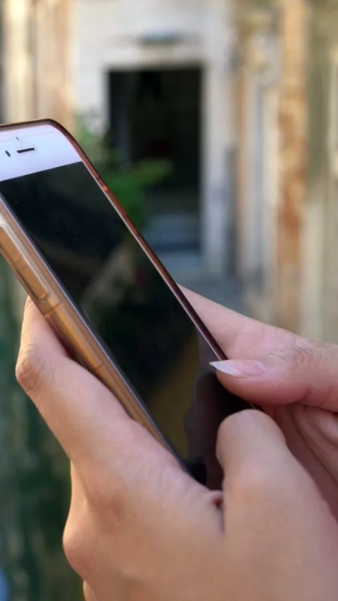 Closeup of asian hands using smartphone in street of Venice with channel Stock Footage 331768676