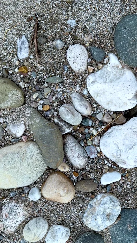 Closeup of assorted pebbles and stones on a sandy beach with diverse textur.. Stock Footage 338414273