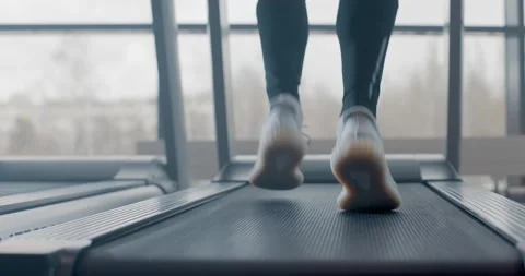 Closeup athletic feet running on treadmill in fitness gym, slow motion. Back Video stock 149483136