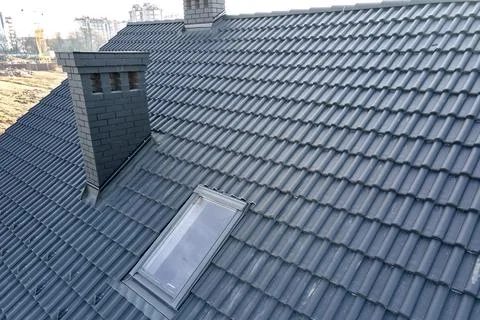 Closeup of attic window and brick chimney on house roof top covered with ceramic Stock Photos