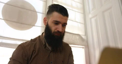 Closeup attractive bearded man looks at the laptop works Stock Footage