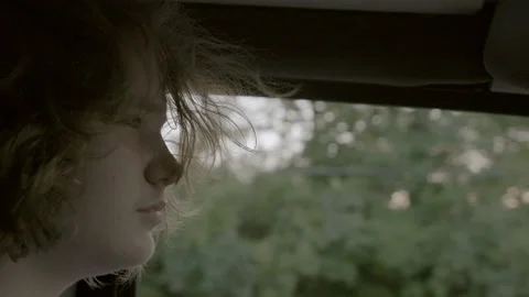 Closeup on attractive teen driving with sunset in window Stock Footage