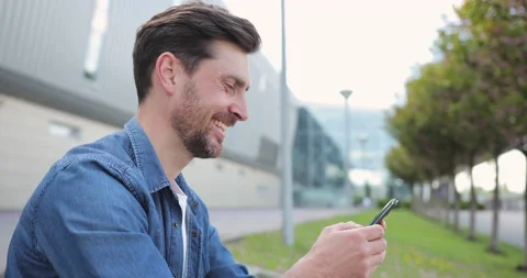 Closeup of attractive young bearded man using smartphone and smiles. Texting Stock Footage 157452344