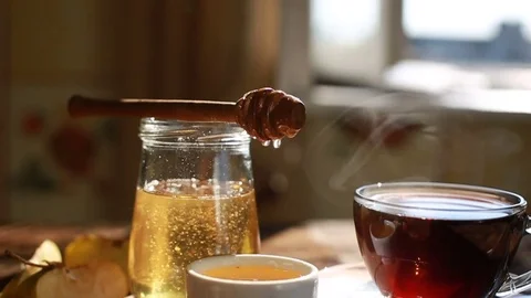 Closeup is authentic honey slowly drains from a spoon. Morning time. Tea Stock Footage 78589747