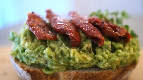 Closeup Of Avocado Toast Bread With Sun Dried Tomatoes Видео 111427164