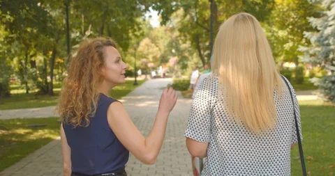 Closeup back view portrait of two caucasian female friends walking in park Stock Footage 114897990