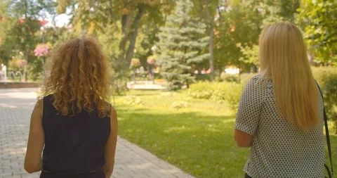 Closeup back view portrait of two pretty caucasian female friends walking in Stock Footage 114899217