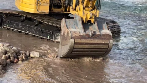 Closeup of backhoe moving around in a rocky river Stock Footage 273176525