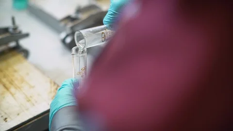 Closeup backside lab worker fills beaker with clear liquid Stock Footage 102303635