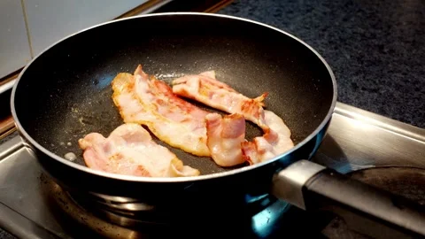 Closeup of bacon frying in a pan then being turned over. Easy breakfast at home. 스톡 동영상 334642302