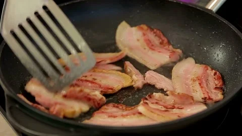 Closeup of bacon frying in a pan then being turned over. Easy breakfast at home. 스톡 동영상 334642446
