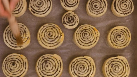 Closeup. Baker covers poppy roll buns before baking. Baking concept. Video stock 101140297