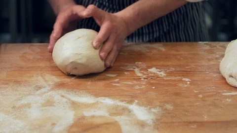 Closeup, baker's hands knead bread dough and spread out into shape Stock Footage 125577566