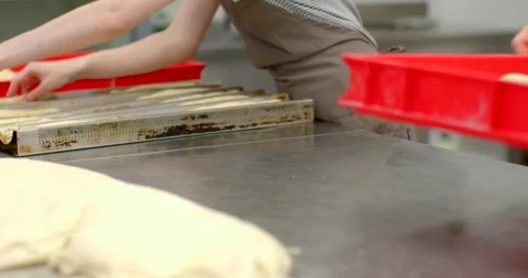 Closeup of bakers shaping dough on stainless steel worktable with trays and Stock Footage 344596531